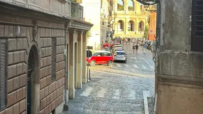 a red car is driving down a city street at Colosseo Design Apartament in Rome