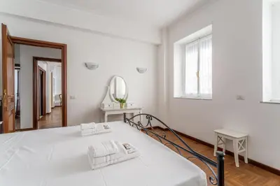 a white bedroom with a bed and a mirror at iFlat Vatican Spacious Apartment with Terrace in Rome