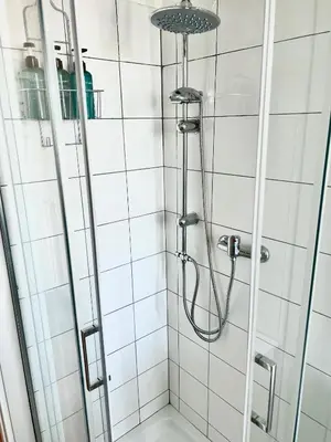 a shower in a bathroom with white tiles at Il Cielo Su Roma San Paolo in Rome