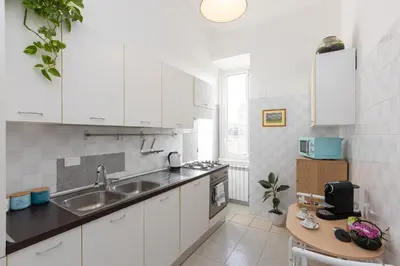 a kitchen with white cabinets and a sink and a table at Cherry Suites- Timeless Roman Residence & Terrace in Rome