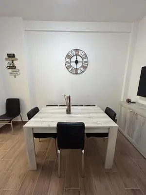 a dining room table with chairs and a clock on the wall at La Casa di Léon - Battistini - Vaticano in Rome