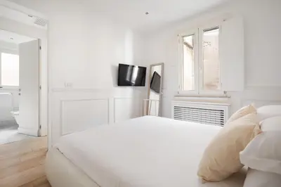 a white bedroom with a white bed and a tv at Crystal Home Piazza Navona in Rome