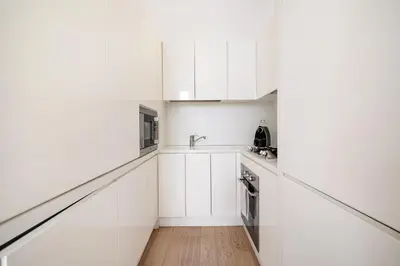 a white kitchen with white cabinets and a wooden floor at Crystal Home Piazza Navona in Rome