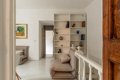 a living room with a chair and a book shelf at GuestHost - Piazza de' Renzi Duplex Apartment in Rome