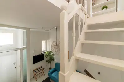 a white staircase in a living room with a blue chair at GuestHost - Piazza de' Renzi Duplex Apartment in Rome