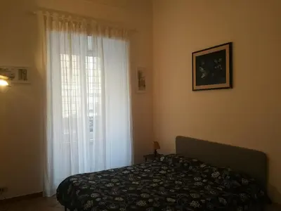 a bedroom with a bed and a window with white curtains at Famy in Rome