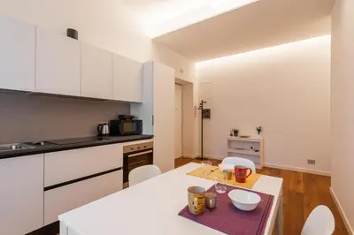 a kitchen with white cabinets and a table and chairs at Elegant Haven Re di Roma by Hostand in Rome