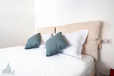 a white bed with three pillows on it at Domus in Lauro in Rome