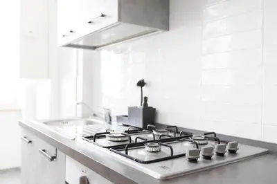a kitchen with a stove top in a white kitchen at Maison Margaret in Rome