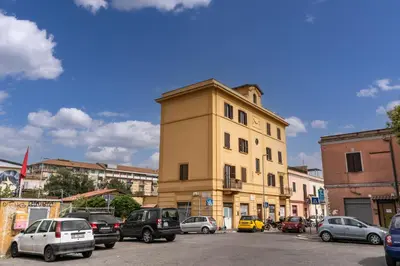 a tall yellow building with cars parked in a parking lot at Pìgneto Roma Good Vibes Apartment in Rome