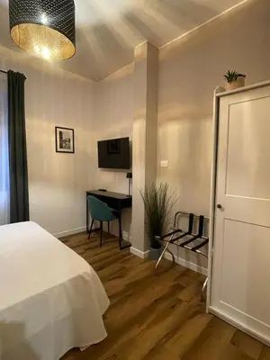 a bedroom with a bed and a desk with a television at Maison Adelaide in Rome
