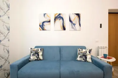 a blue couch in a living room with two paintings at Design Flat - Nel Centro di Roma in Rome