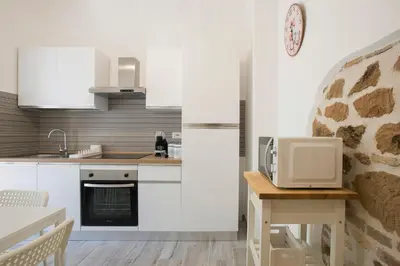 a kitchen with white cabinets and a table with a microwave at Design Flat - Nel Centro di Roma in Rome