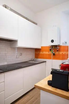 a kitchen with white cabinets and a wooden counter at Washington TownHouse - Roma Statuto in Rome