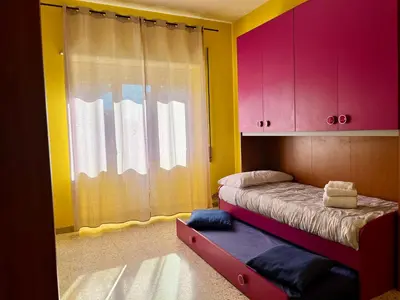 a bedroom with a bed with pink and yellow walls at Sweet Holiday Gardenie in Rome