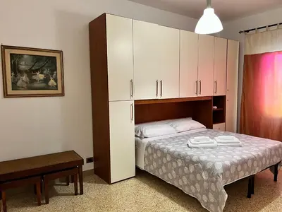 a bedroom with a bed with white sheets and cabinets at Sweet Holiday Gardenie in Rome