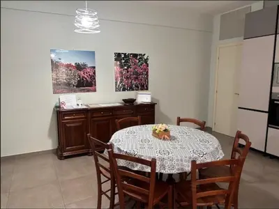 a dining room with a table and chairs and a kitchen at Sweet Holiday Gardenie in Rome