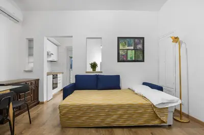 a bedroom with a blue bed and a kitchen at Cavour 172 - Monti Apartment near Colosseum by RHR in Rome