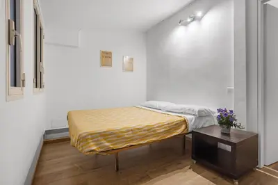 a bed in a white room with a table at Cavour 172 - Monti Apartment near Colosseum by RHR in Rome