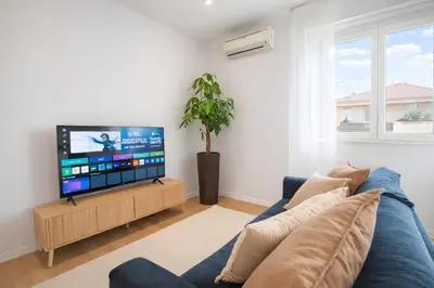 a living room with a blue couch and a flat screen tv at Sunny Monteverde Apartment - Near Trastevere by RHR in Rome