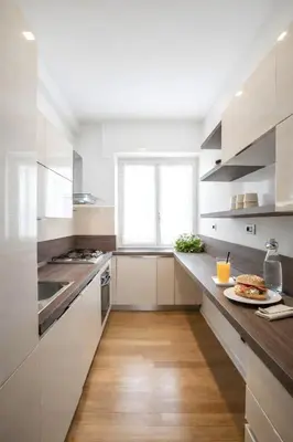 a kitchen with white cabinets and a wooden floor at Sunny Monteverde Apartment - Near Trastevere by RHR in Rome
