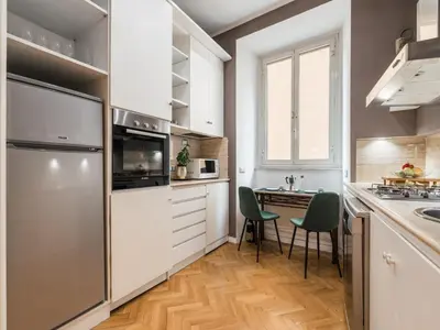 a kitchen with white cabinets and a table with chairs at The Best Rent - Splendid three-bedroom apartment near the Trevi Fountain in Rome