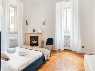 a white bedroom with two beds and a chair at The Best Rent - Splendid three-bedroom apartment near the Trevi Fountain in Rome