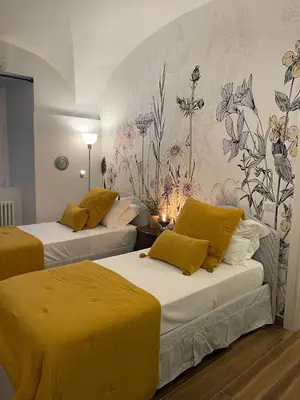 two beds in a room with flowers on the wall at Giorgina Garden&Rooms in Rome