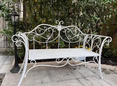 a white bench sitting in front of a fence at Giorgina Garden&Rooms in Rome