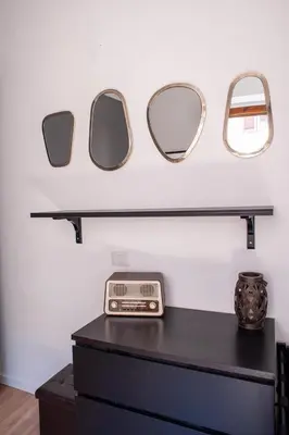 three mirrors on a shelf above a black dresser at Casa Luce 66 in Rome