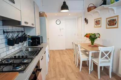 a kitchen with a table and chairs and a kitchen with white cabinets at Casa Luce 66 in Rome