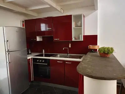 a kitchen with red cabinets and a stainless steel refrigerator at DELIGHTFUL LOFT IN PlGNETO in Rome
