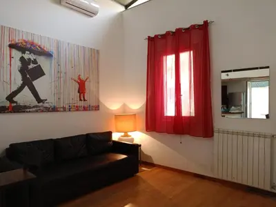 a living room with a black couch and a red curtain at DELIGHTFUL LOFT IN PlGNETO in Rome