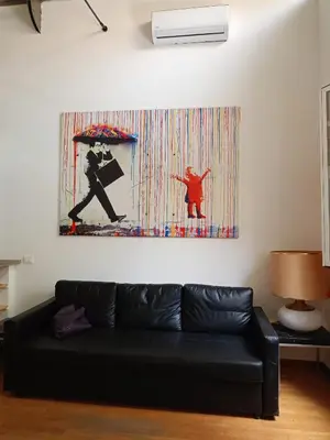 a black couch in a living room with a painting on the wall at DELIGHTFUL LOFT IN PlGNETO in Rome
