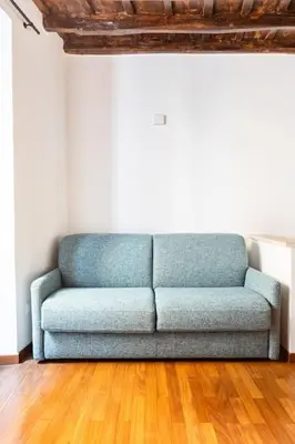 a blue couch in a room with a wooden floor at Bottega Augustea Duplex apartment in Monti in Rome