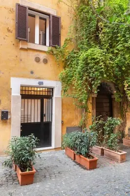 a building with three plants in front of a door at Bottega Augustea Duplex apartment in Monti in Rome