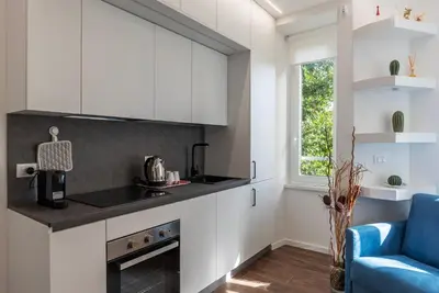 a kitchen with white cabinets and a blue chair at GuestHost - Monteverde Classy Apartment in Rome
