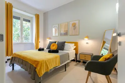 a bedroom with a bed with a yellow blanket and a chair at Mustard Apartment S Camillo - Holiday Homes Rome in Rome
