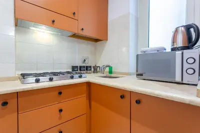 a kitchen with orange cabinets and a microwave at Mustard Apartment S Camillo - Holiday Homes Rome in Rome