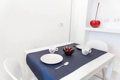 a white table with plates and cups and an apple at Appartamento Basilica di San Giovanni in Laterano in Rome