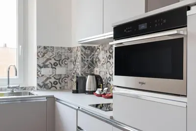 a white kitchen with a microwave and a sink at Appartamento Basilica di San Giovanni in Laterano in Rome