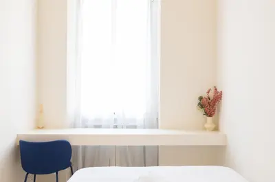 a bedroom with a bed and a window with a blue chair at Reale Vatican House in Rome