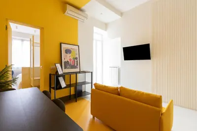 a living room with a table and a yellow couch at Reale Vatican House in Rome