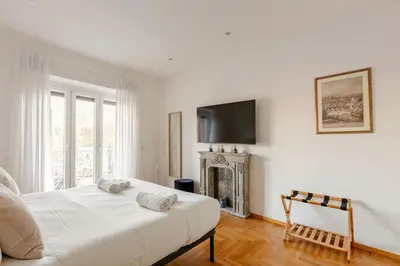 a white bedroom with a bed and a television at Roma Vatican City in Rome