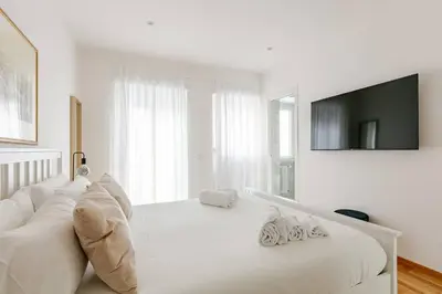 a white bedroom with a white couch and a tv at Roma Vatican City in Rome