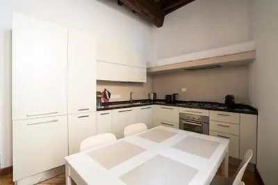 a white kitchen with a white table and chairs at Rome Center Apartment Campo De' Fiori in Rome