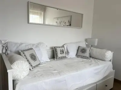 a white bed with pillows and a mirror on the wall at Le Buganville in Rome