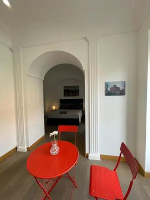 a room with a red table and chairs and a bed at Giulia Mesa Suites in Rome
