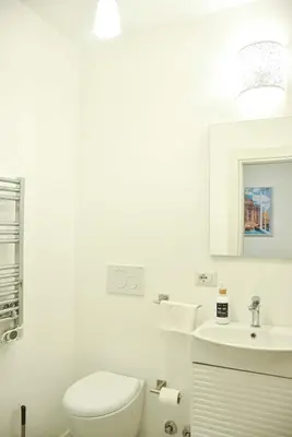 a white bathroom with a toilet and a sink at Giulia Mesa Suites in Rome