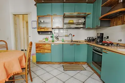 a kitchen with turquoise cabinets and a table with a table at Appartamento a Roma a due passi da Trastevere in Rome